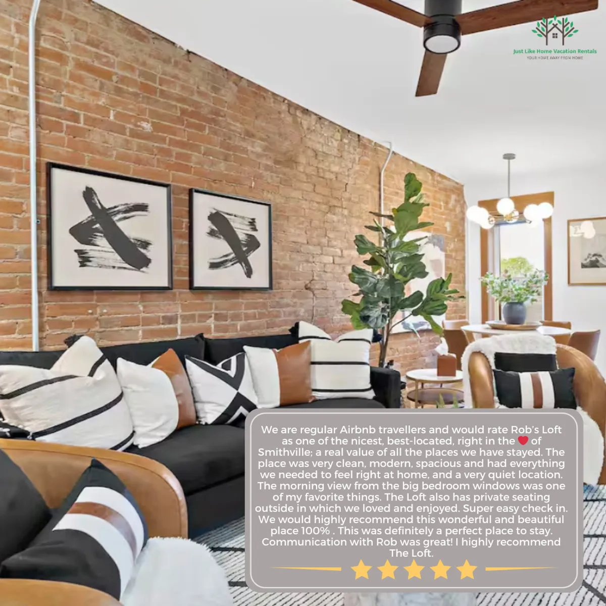 A bright open-plan living area featuring an exposed brick wall, abstract art, and a chic seating arrangement with a green plant accent. The space is filled with natural light streaming through large windows, highlighting the modern decor and comfortable furnishings.