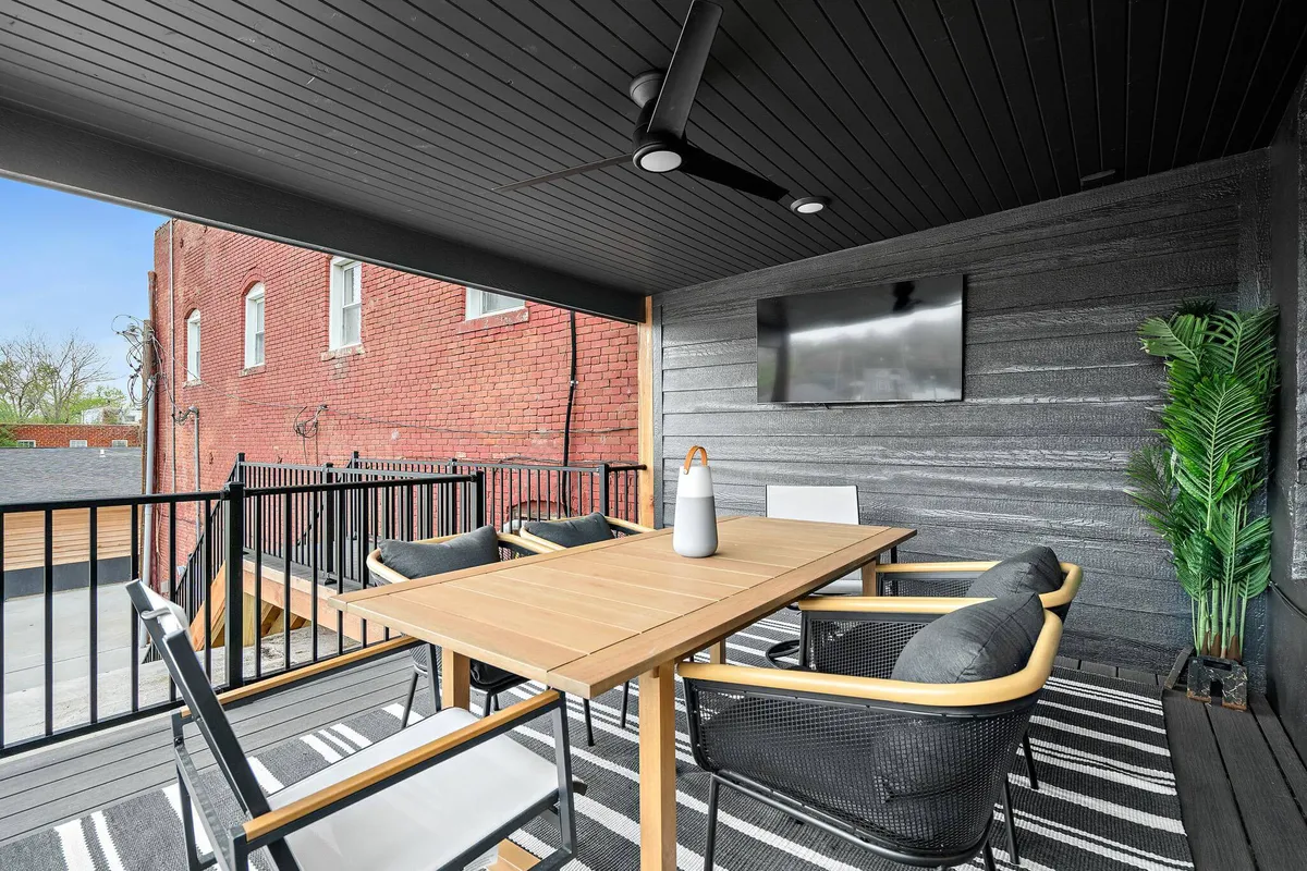 A comfortable exterior deck with a dining table, outdoor seating, potted plant, and a television. The wooden deck creates a seamless indoor-outdoor experience, ideal for entertaining or relaxing in the fresh air.